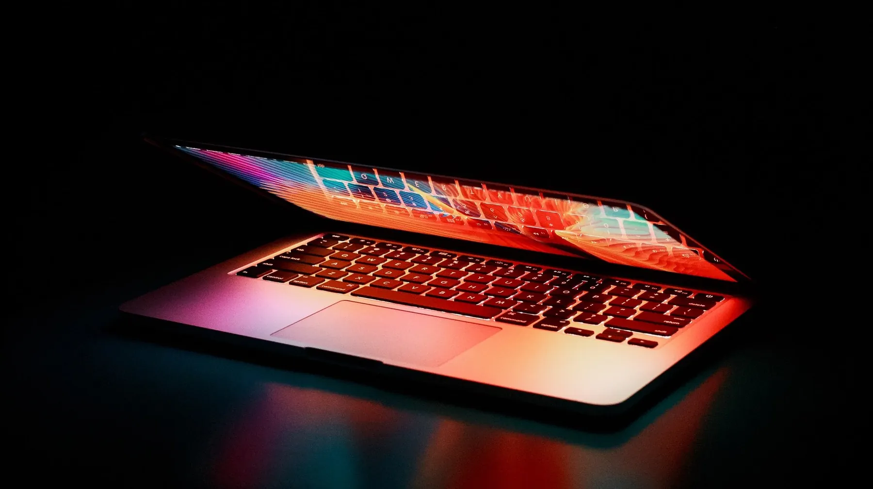 Aufgeklappter Laptop im Dunkeln, vom Bildschirm rot beleuchtet